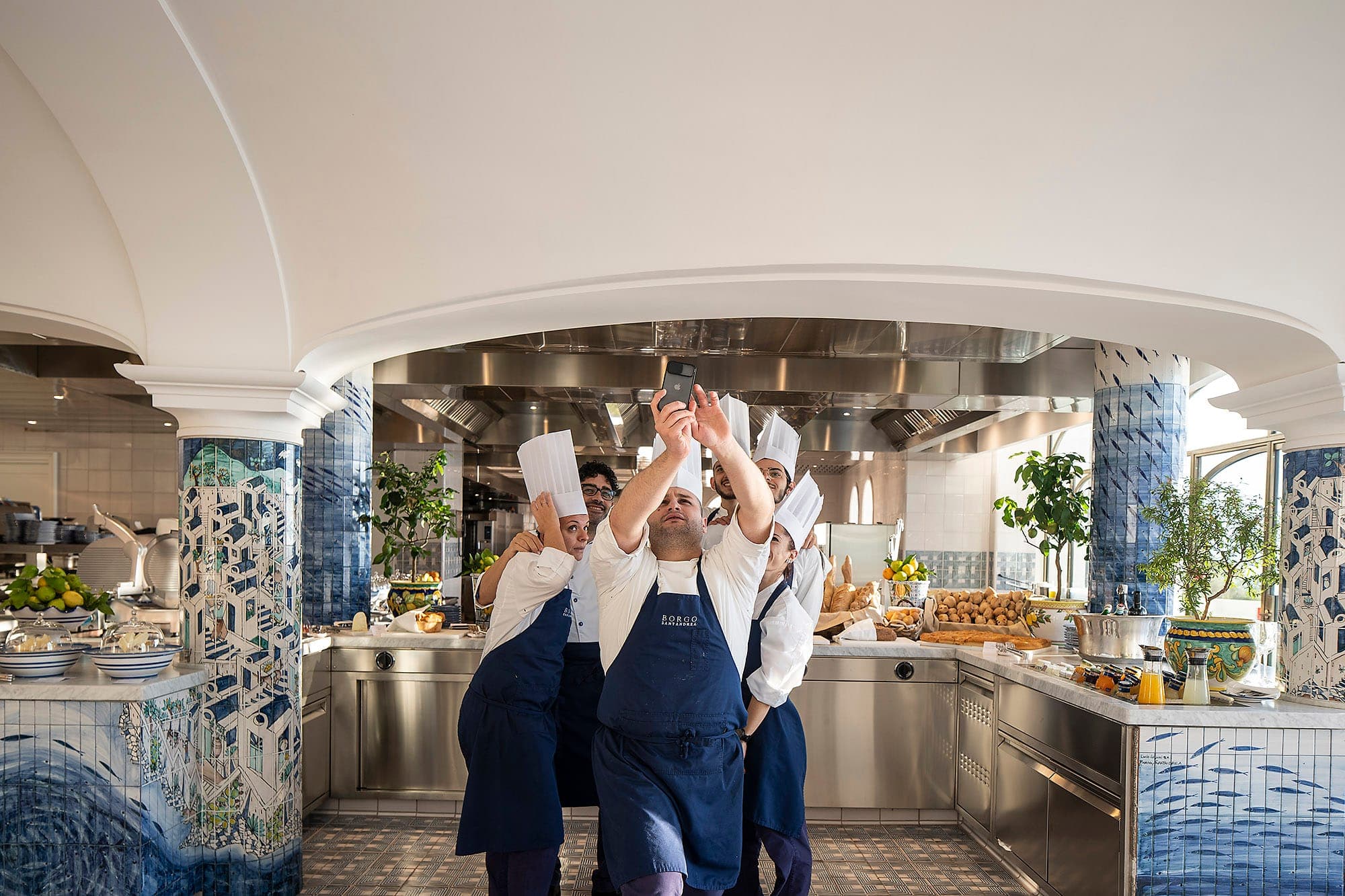 La brigata al completo in cucina, sotto l'arco bianco e i pilastri in maiolica.